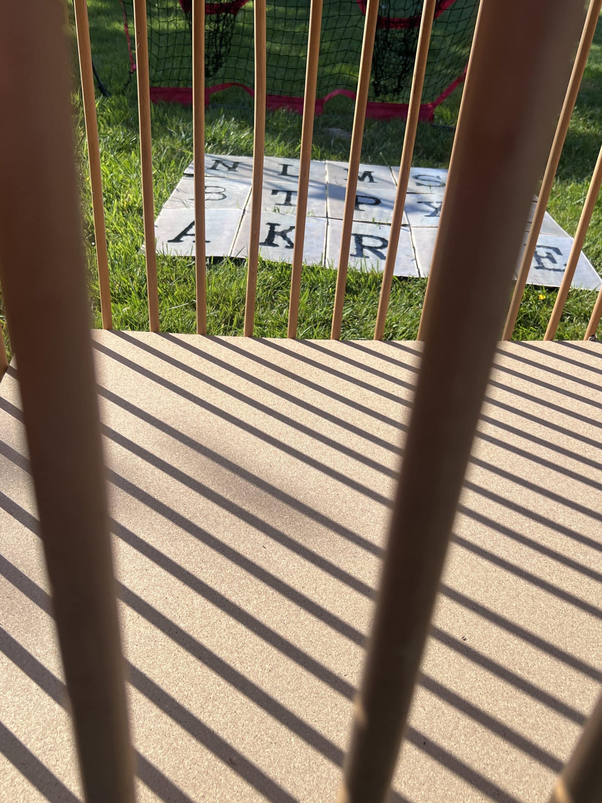 grille en bois avec au deuxième des lettres étalées au sol
