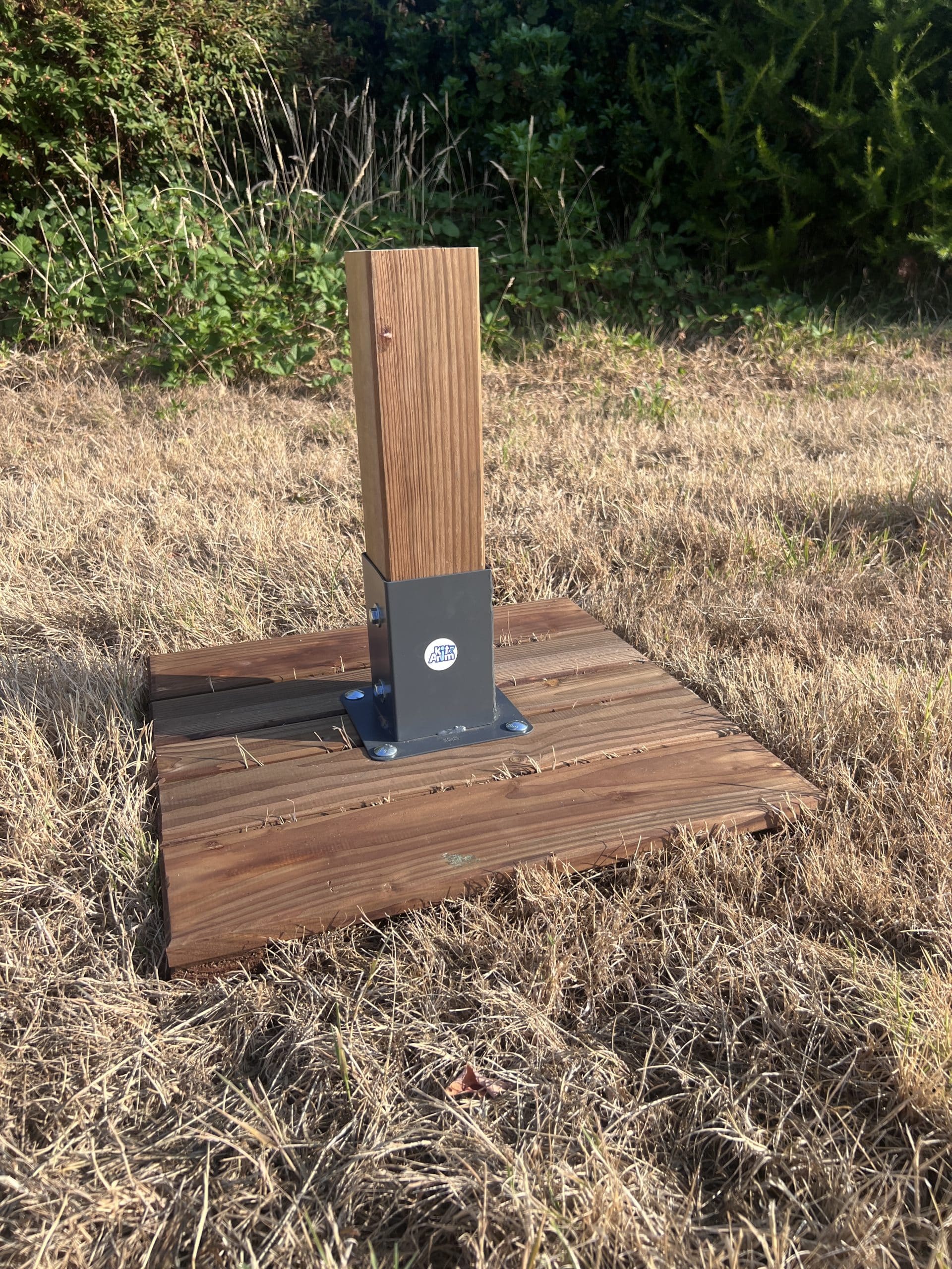 un poteau en bois avec un socle en bois posé au sol