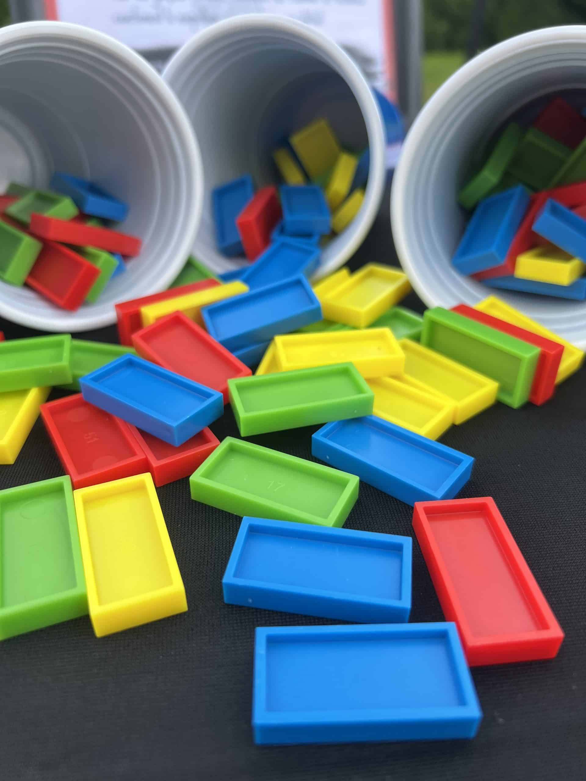 Lots de dominos étalés et 3 gobelets en arriÚre plan contenant des dominos