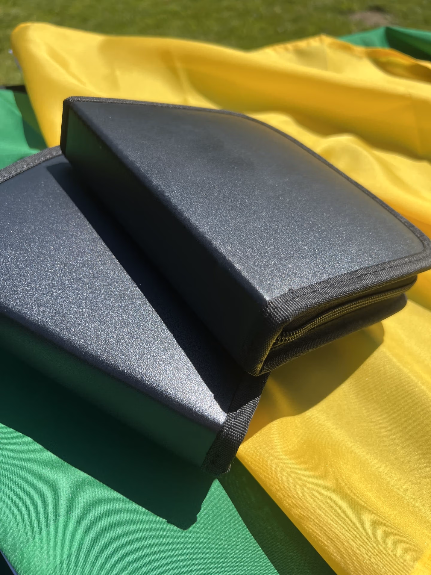 deux valisettes noires fermées posées sur deux drapeaux vert et jaune