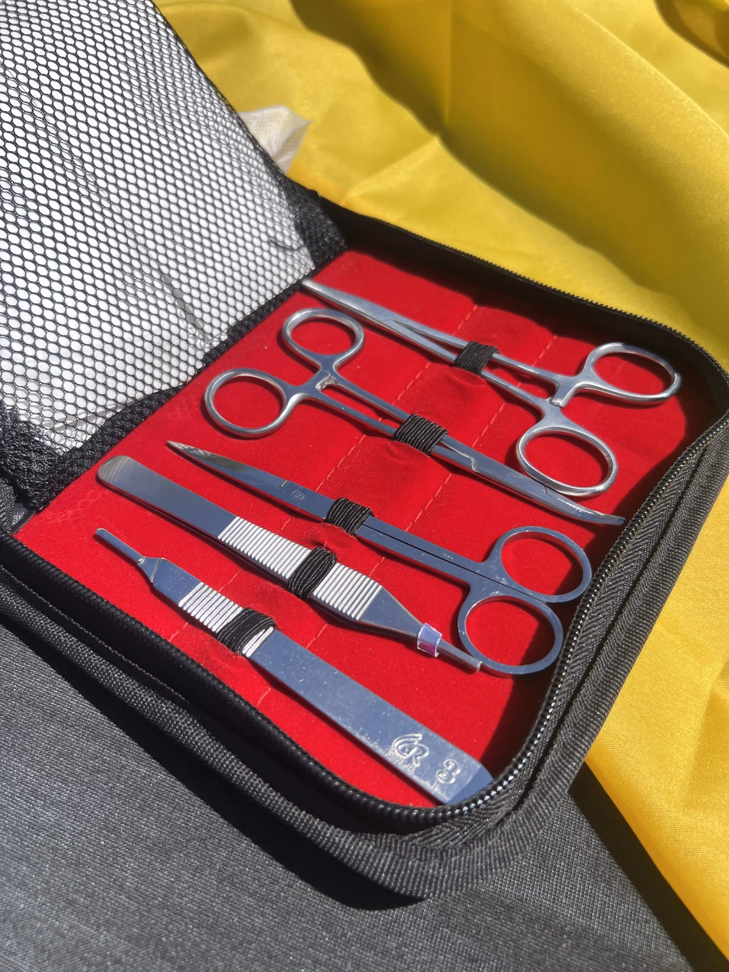 Valisette de suture ouverte avec vue sur les ciseaux et autres outillages de suture